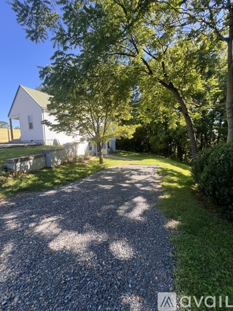 A gravel path leads to a white house with a green roof.