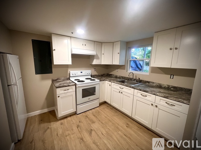 A kitchen with white cabinets and a black screen on the wall.