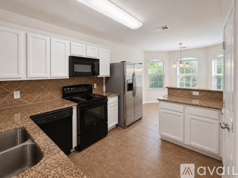 A kitchen with black appliances and white cabinets.