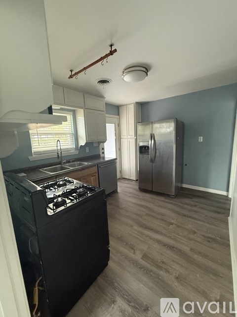 A kitchen with a black stove top oven and a refrigerator.