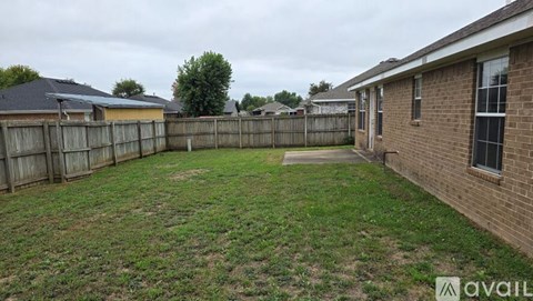 A backyard with a wooden fence and a grassy area.