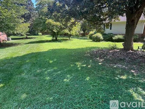A well-maintained lawn with a tree and a house in the background.