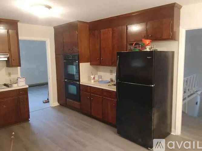 A kitchen with a black refrigerator and wooden cabinets.
