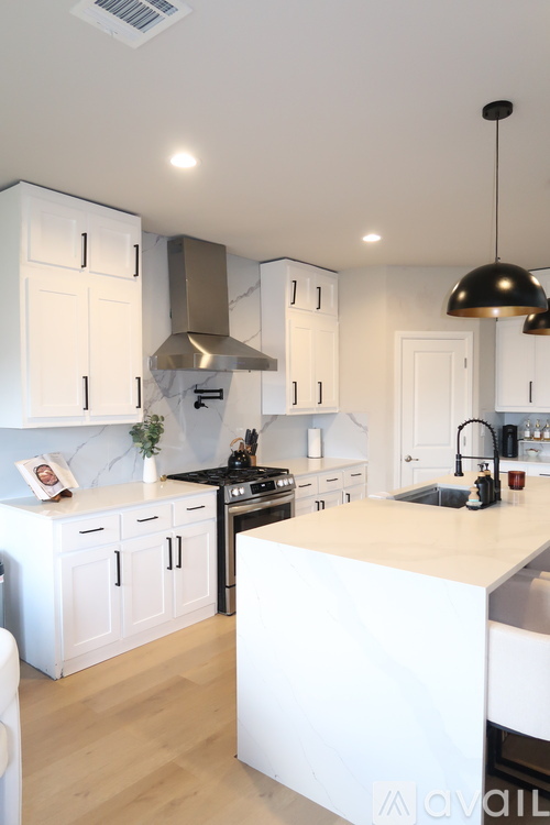 A kitchen with white cabinets and a black hood.