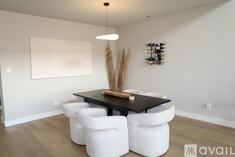 A modern dining room with a black table and white chairs.