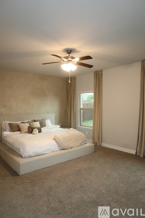 A bedroom with a bed, a ceiling fan, and a window with curtains.