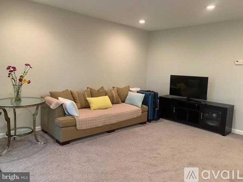 A living room with a sofa, a glass table, and a television.