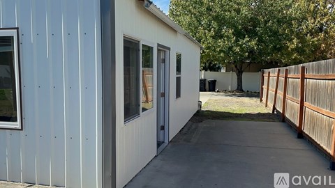 A small white building with a wooden fence in front.