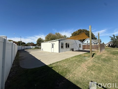 A white building with a brown roof is surrounded by a white fence.
