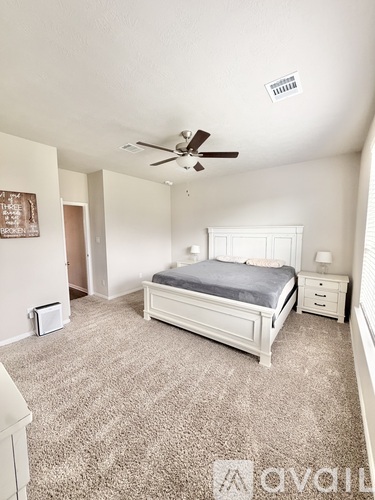 A bedroom with a bed, nightstand, and a ceiling fan.
