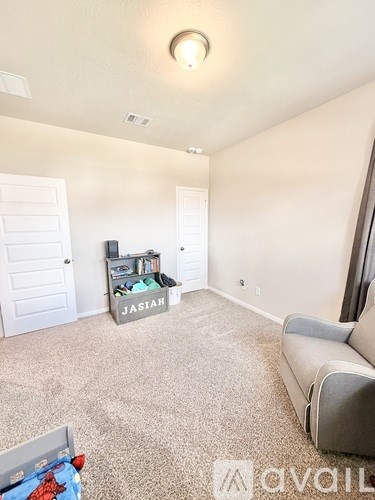 A living room with a grey couch and a box labeled "Jasiah" on the floor.