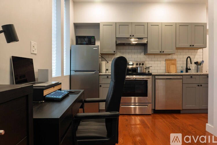 A kitchen with a black chair and a laptop on a desk.