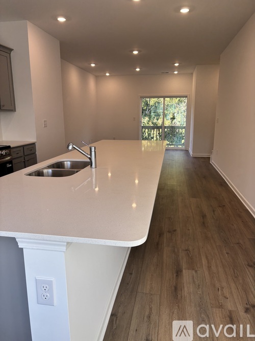 A kitchen with a sink and wooden floors.
