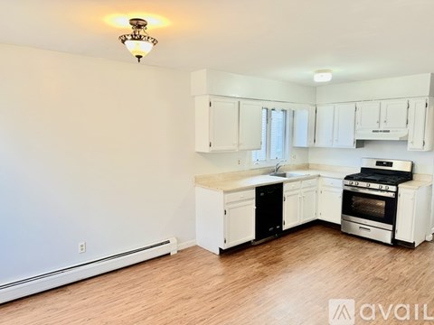 A kitchen with white cabinets and appliances is available for rent.