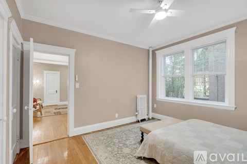 A bedroom with a bed, a window, and a fan.