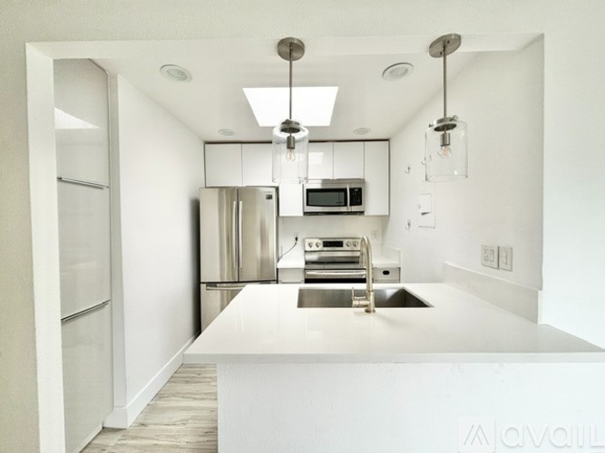A modern kitchen with a white countertop and stainless steel appliances.