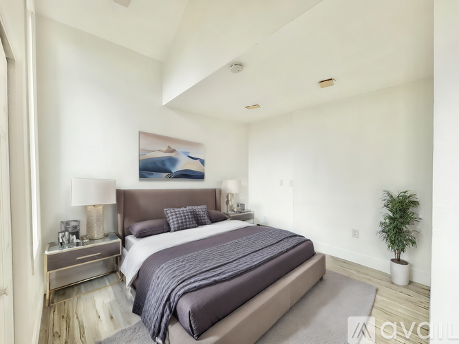 A bedroom with a large bed and a painting on the wall.
