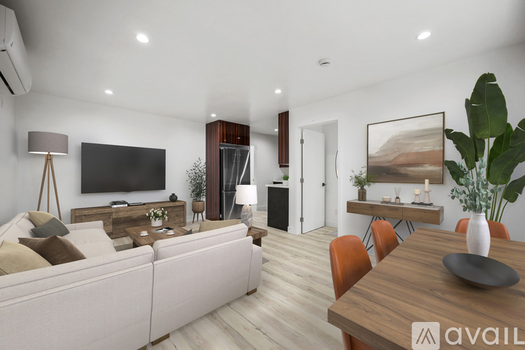 A modern living room with a white sofa, wooden dining table, and a painting on the wall.