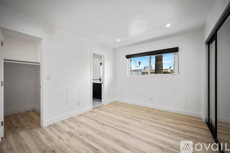 A spacious room with wooden flooring and a window overlooking a street.