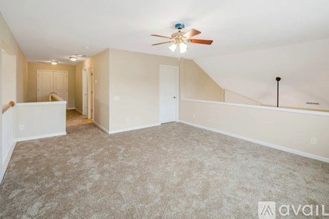 A spacious room with a ceiling fan and carpeted floor.