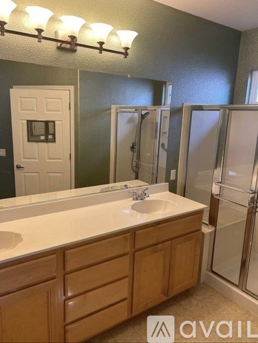 A bathroom with a sink, mirror, and shower.