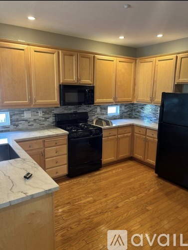 A kitchen with wooden cabinets and black appliances.