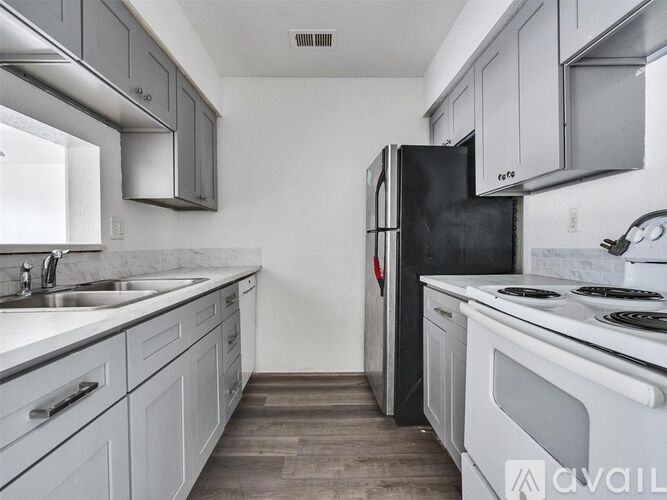 A kitchen with a black refrigerator and white appliances.