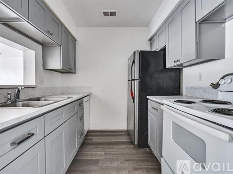 A kitchen with a black refrigerator and white appliances.