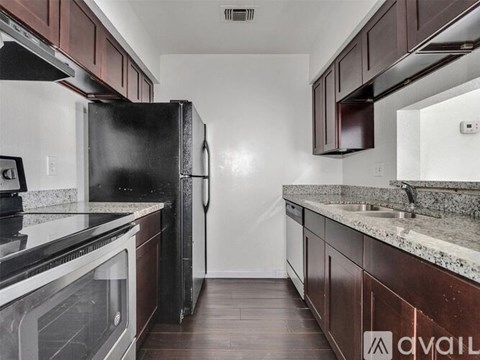A kitchen with dark wood cabinets and a black refrigerator.