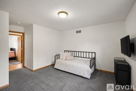 A bedroom with a white bed and a television on the wall.