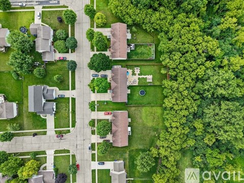 A bird's eye view of a suburban neighborhood with houses, trees, and a street.