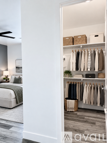 A bedroom with a bed and a wardrobe with clothes hanging.