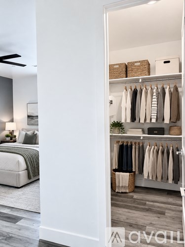 A bedroom with a bed and a wardrobe with clothes hanging.
