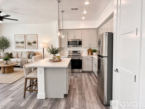 A modern kitchen with a dining table and chairs, a refrigerator, and a ceiling fan.