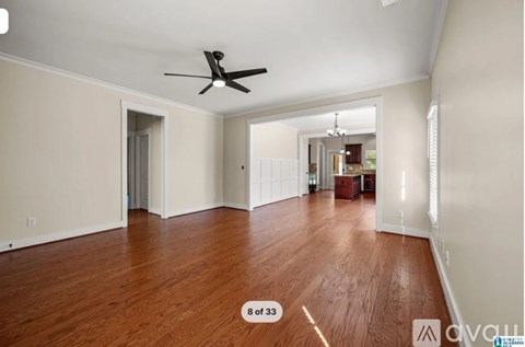 A spacious room with a ceiling fan and wooden flooring.