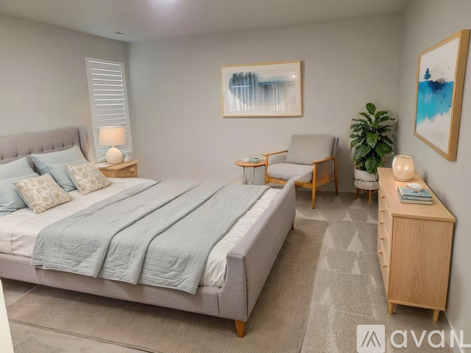 A bedroom with a large bed and a painting on the wall.