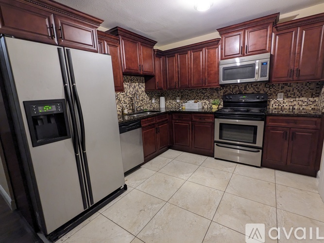 A kitchen with a refrigerator, microwave, oven and cabinets.