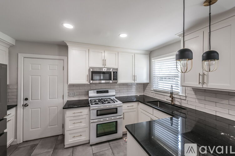 A kitchen with white cabinets and black countertops.
