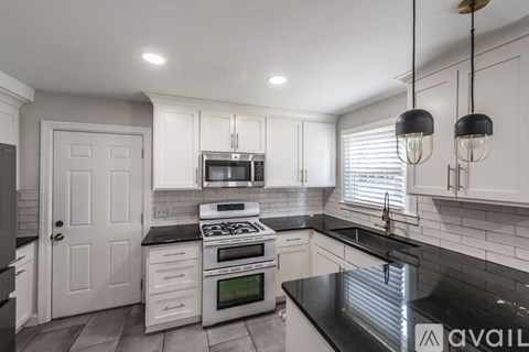 A kitchen with white cabinets and black countertops.