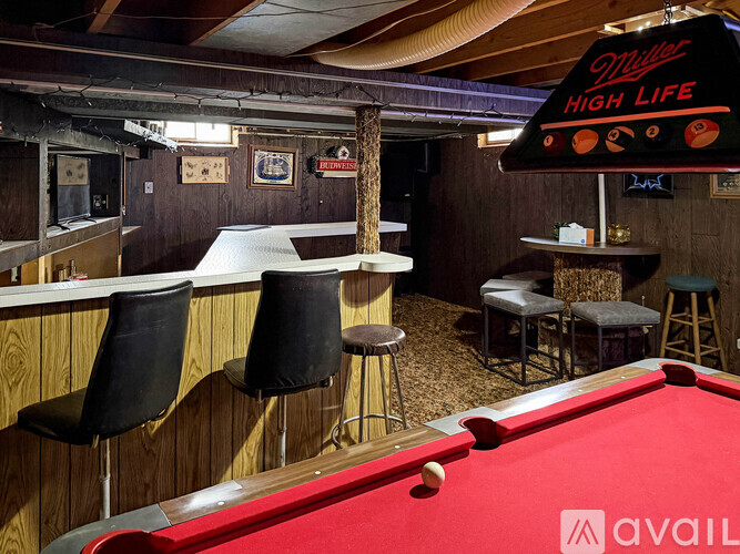 A pool table is in the middle of a room with a bar and a sign that says "Milner High Life".