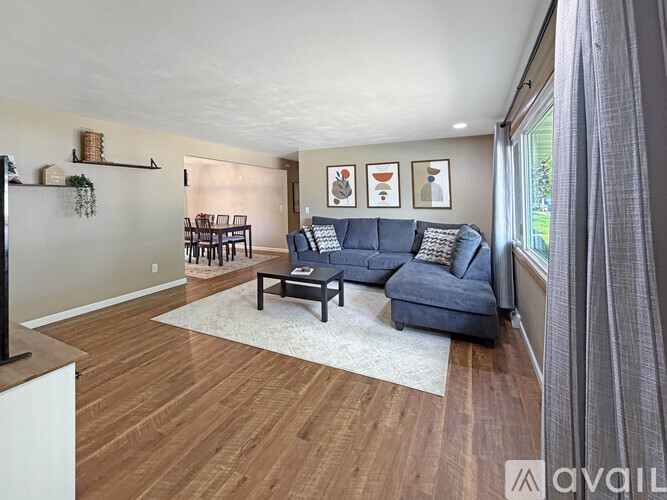 A living room with a blue couch and a white rug.