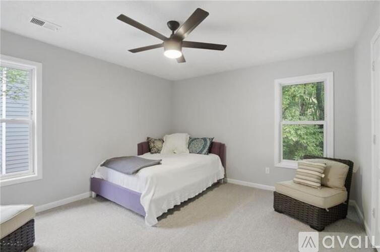 A bedroom with a bed, a chair, and a ceiling fan.