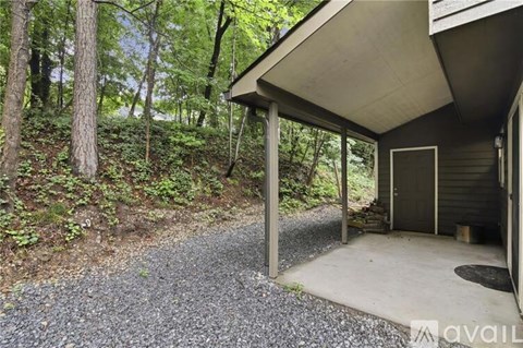 A gravel path leads to a small building in a wooded area.