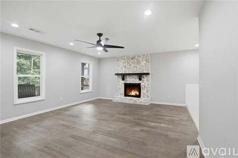 A spacious living room with a fireplace and a ceiling fan.