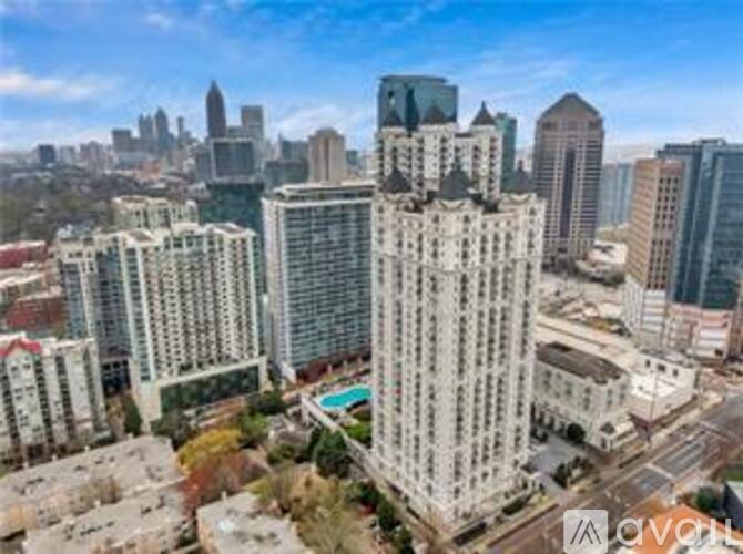 A cityscape with a tall building in the foreground and a pool on the roof.
