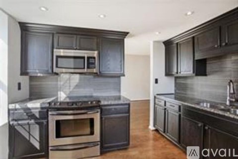 A modern kitchen with dark cabinets and stainless steel appliances.
