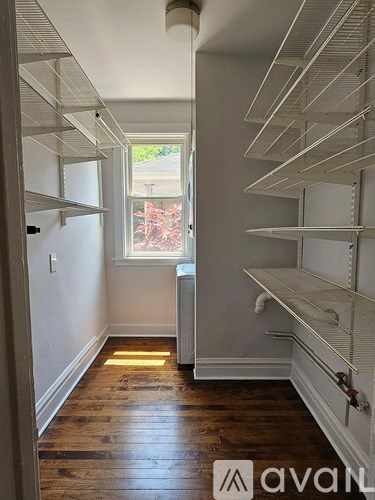 A long hallway with a window and shelving on the side.