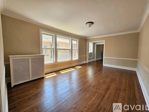 A room with wooden floors and a window with a view of a building outside.