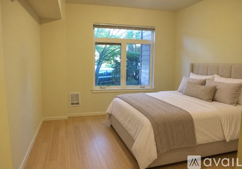 A bedroom with a bed, pillows, and a window.