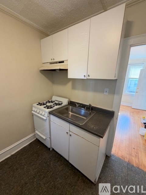 A kitchen with white cabinets and a stove top oven.